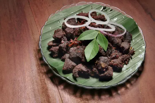 Kerala-style beef roast served on a banana leaf with onion and curry leaves