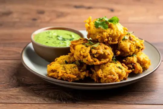 A plate of onion bhaji served with mint and lime chutney